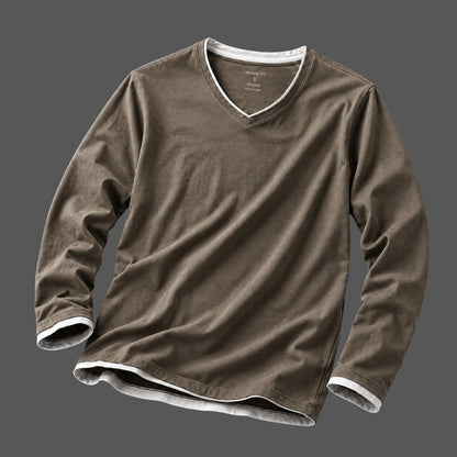 A brown long-sleeve V-neck t-shirt with white ribbed trim along the collar, cuffs, and hem, displayed against a solid dark gray background.