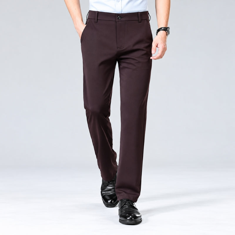 A person wearing dark brown straight-leg dress pants with a white shirt and black dress shoes, shown from the waist down against a light gray studio background.