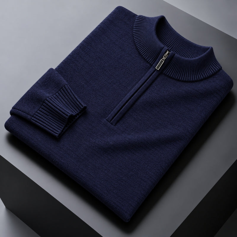A folded navy blue knit sweater with a quarter-zip mock neck collar, displayed on a dark gray geometric surface.