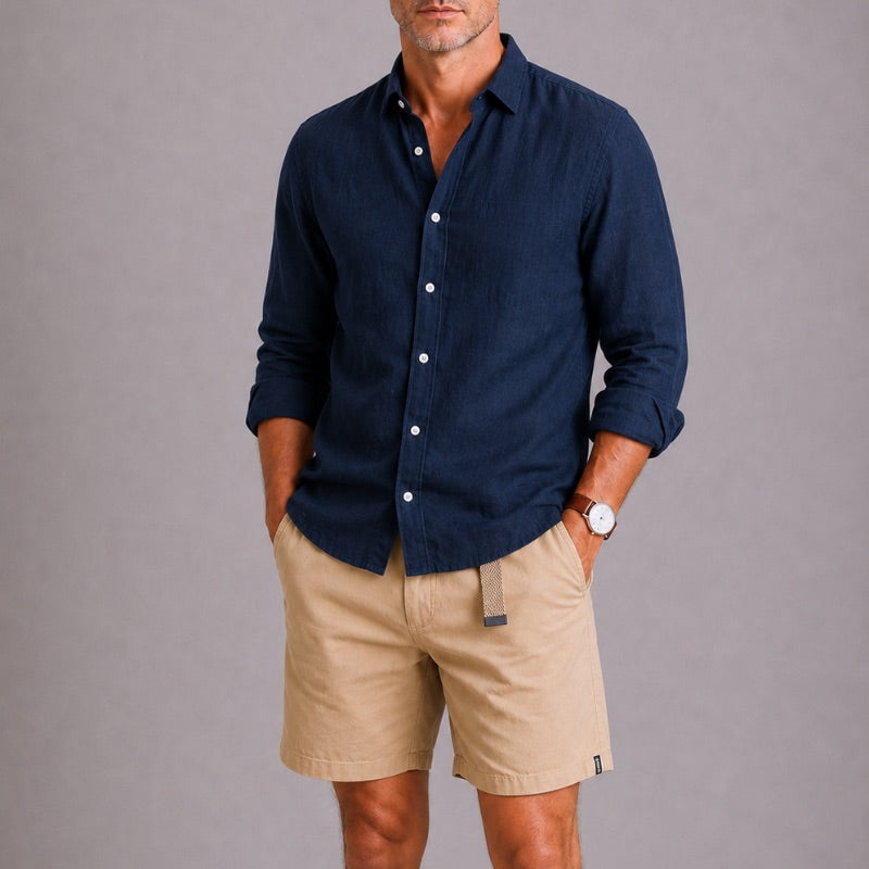 Man wearing a navy button-up shirt and beige shorts against a gray background