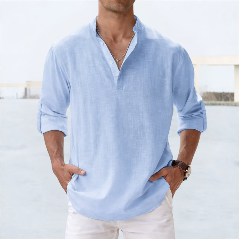Man wearing a light blue long-sleeve shirt with a blurred background