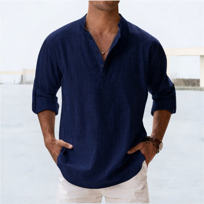 Man wearing a navy blue shirt with rolled-up sleeves against a light background