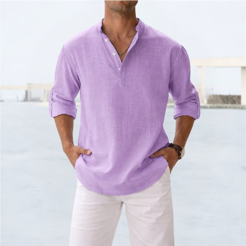 Man wearing a light purple shirt and white pants with a blurred background
