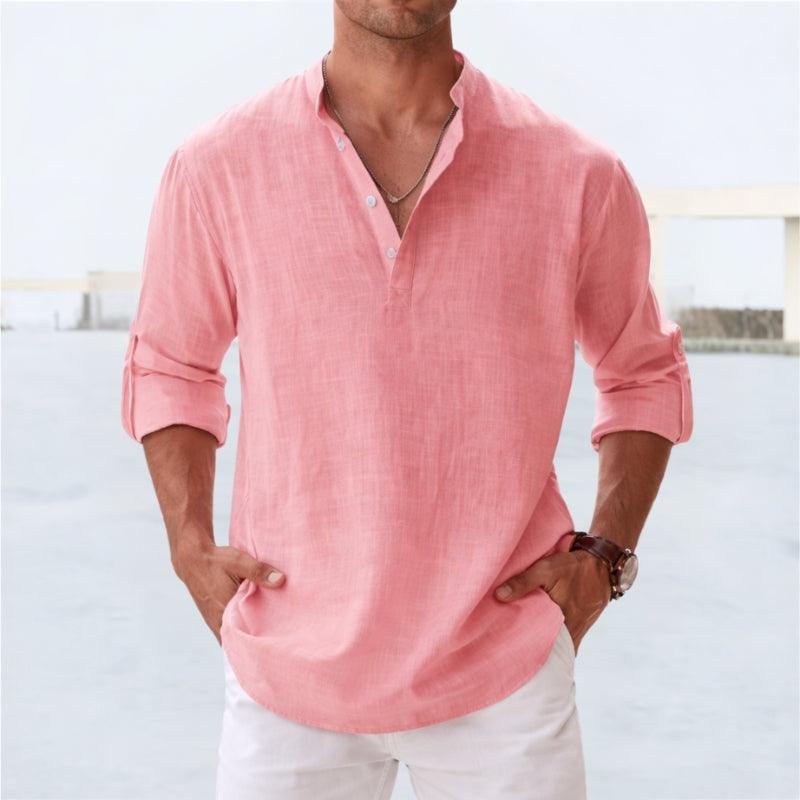 Man wearing a salmon shirt with rolled-up sleeves against a light background