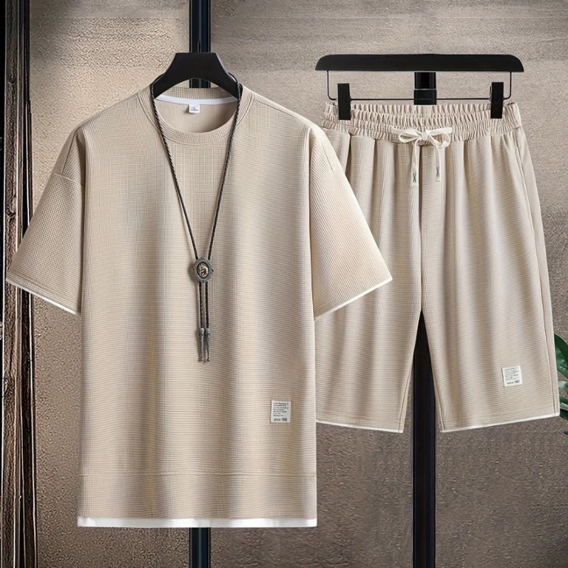 Beige t-shirt and shorts set on hangers against a neutral background