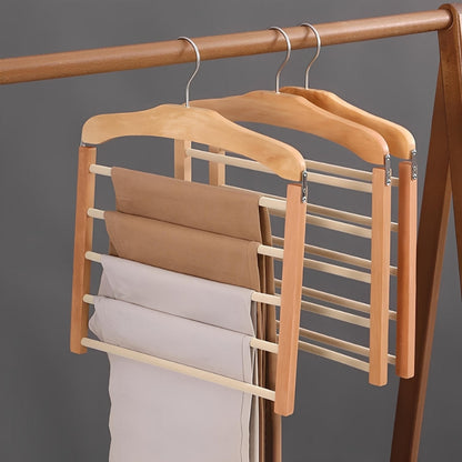 Wooden hanger with multiple tiers holding folded pants against a gray background