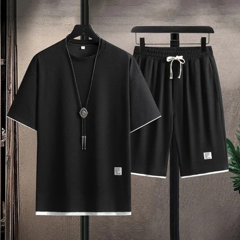 Black t-shirt and shorts set on hangers against a gray background