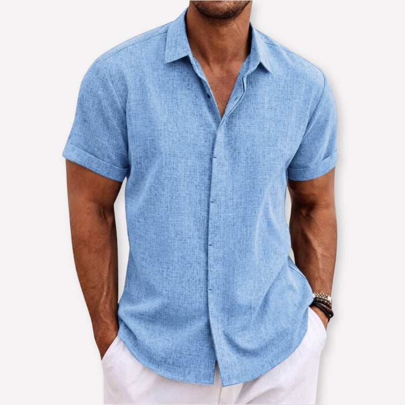 Man wearing a light blue short-sleeve shirt against a white background