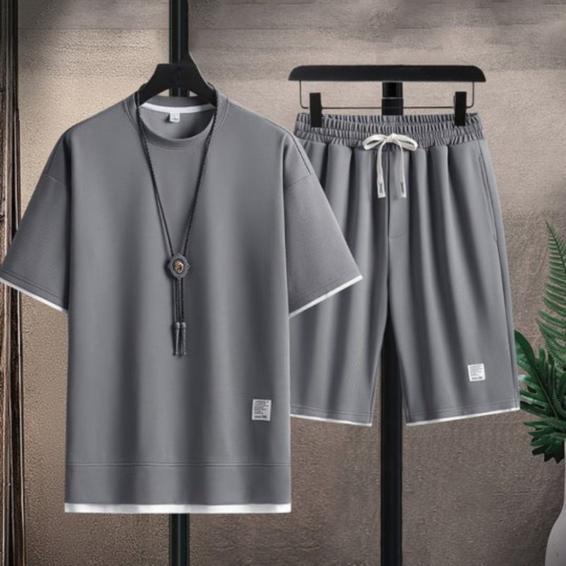 Gray t-shirt and shorts set on hangers against a neutral background