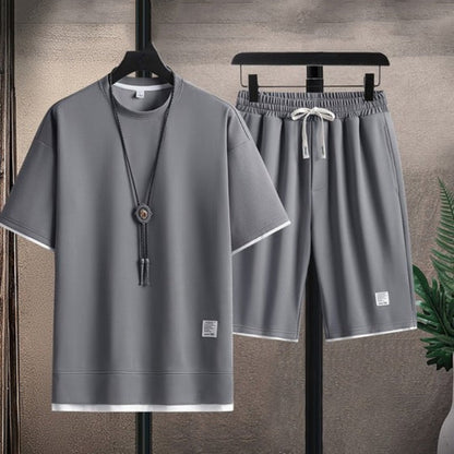 Gray t-shirt and shorts set on hangers against a neutral background