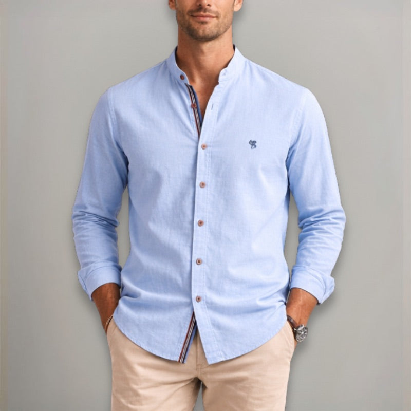Man wearing a light blue button-up shirt with a gray background
