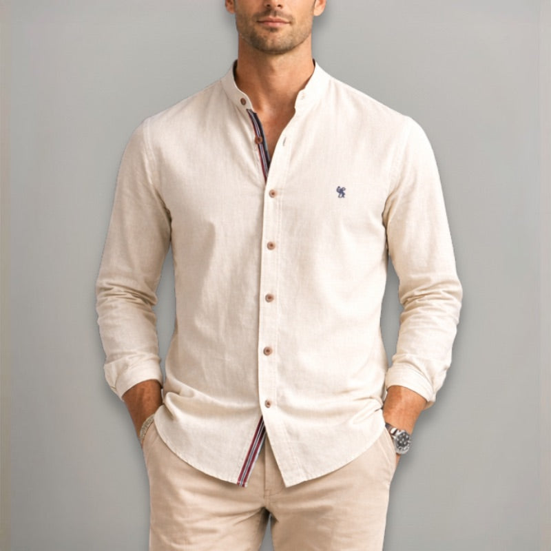 Man wearing a light khaki shirt with a collar and buttons, standing against a plain background.