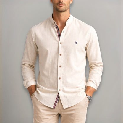 Man wearing a light khaki shirt with a collar and buttons, standing against a plain background.