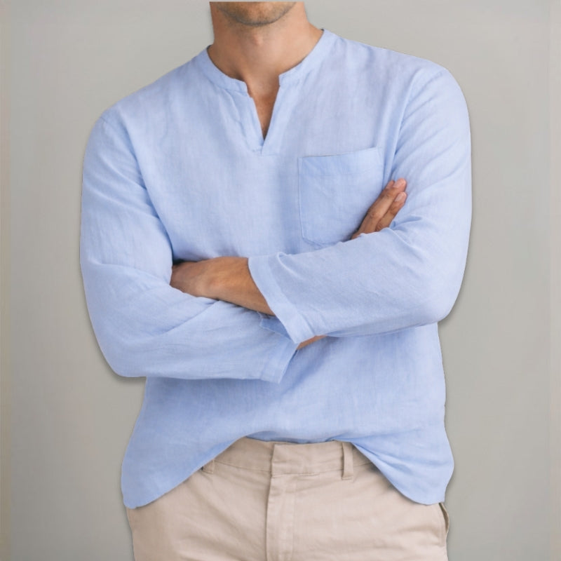 Person wearing a light blue long-sleeve shirt with a neutral background