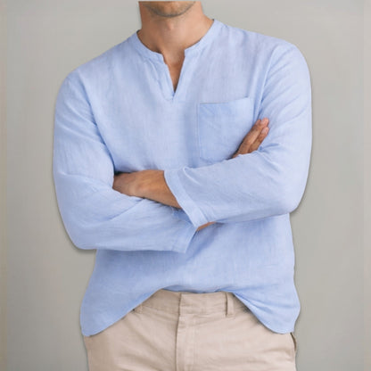 Person wearing a light blue long-sleeve shirt with a neutral background