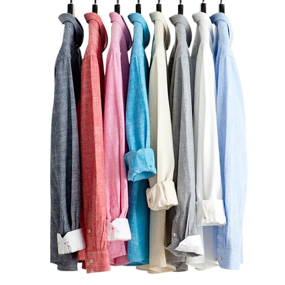 Row of colorful shirts hanging on a rack against a white background