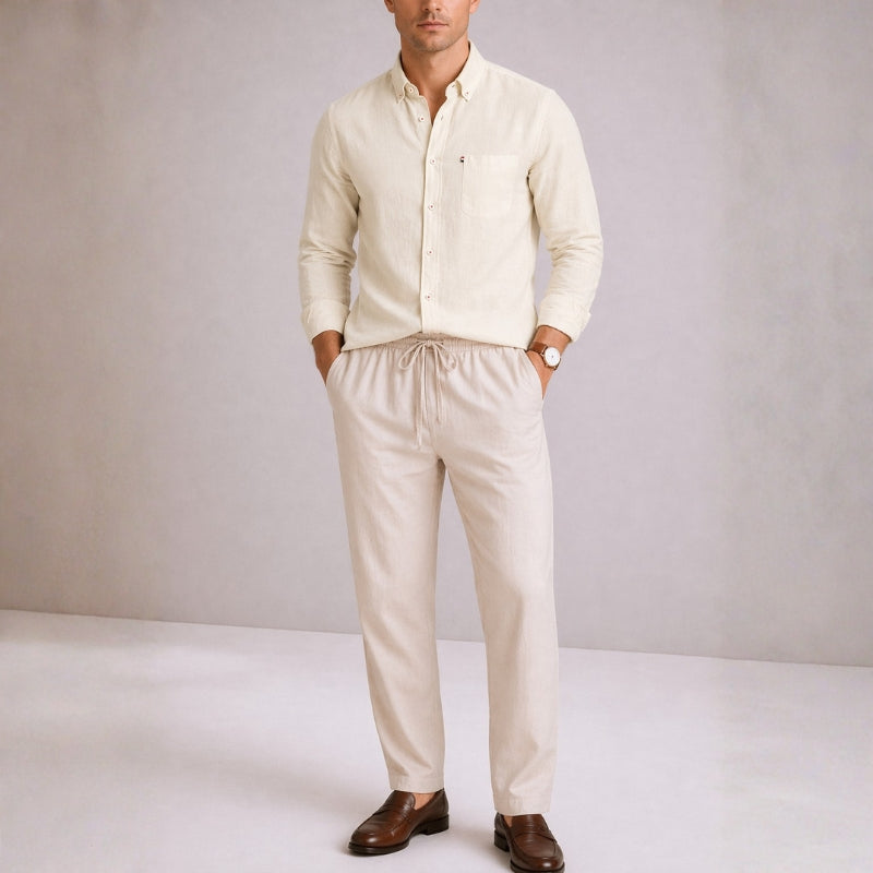 Man wearing a beige shirt and pants with brown shoes on a plain background
