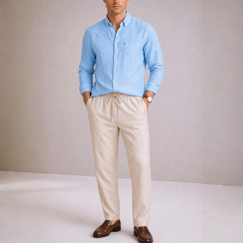 Man wearing a light blue shirt and beige pants against a plain background