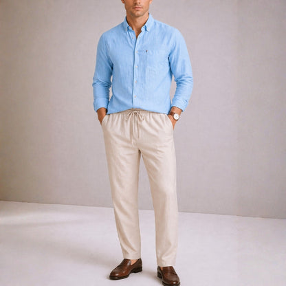 Man wearing a light blue shirt and beige pants against a plain background