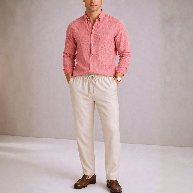 Man wearing a red salmon shirt and beige pants against a plain background