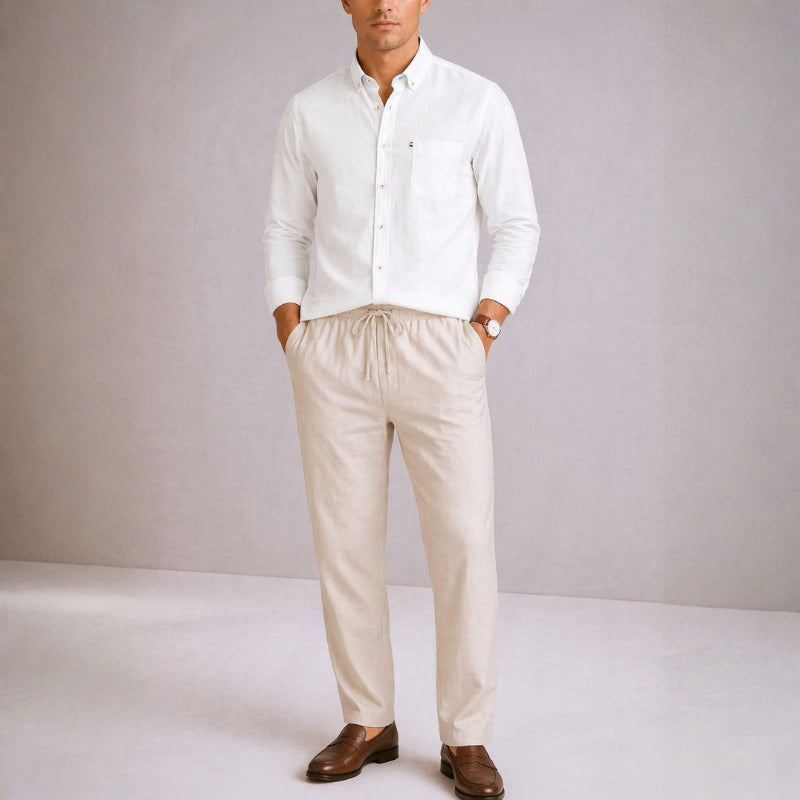 Man wearing a white shirt and beige pants against a plain background