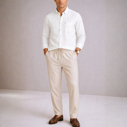 Man wearing a white shirt and beige pants against a plain background