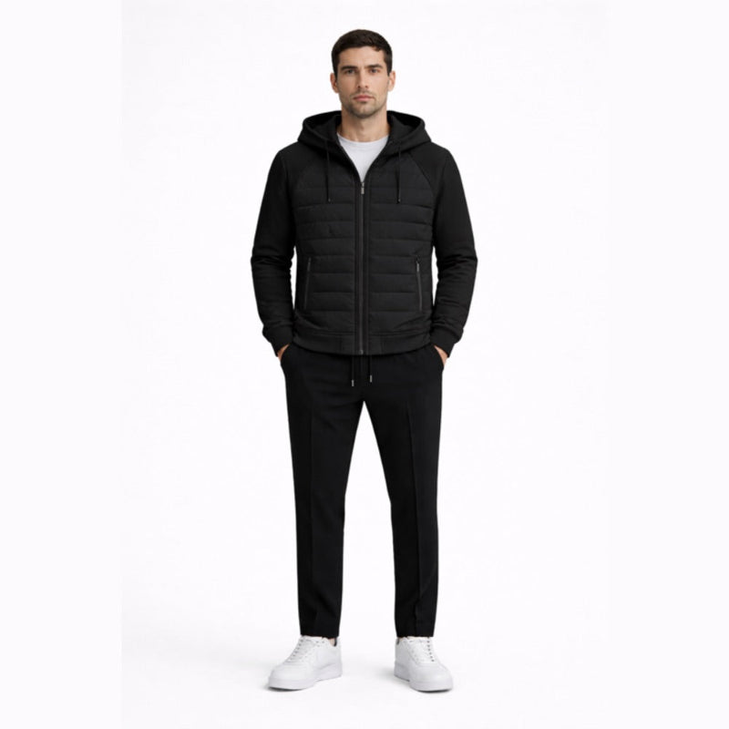 Man wearing a blackquilted jacket, black pants, and white shoes on a white background