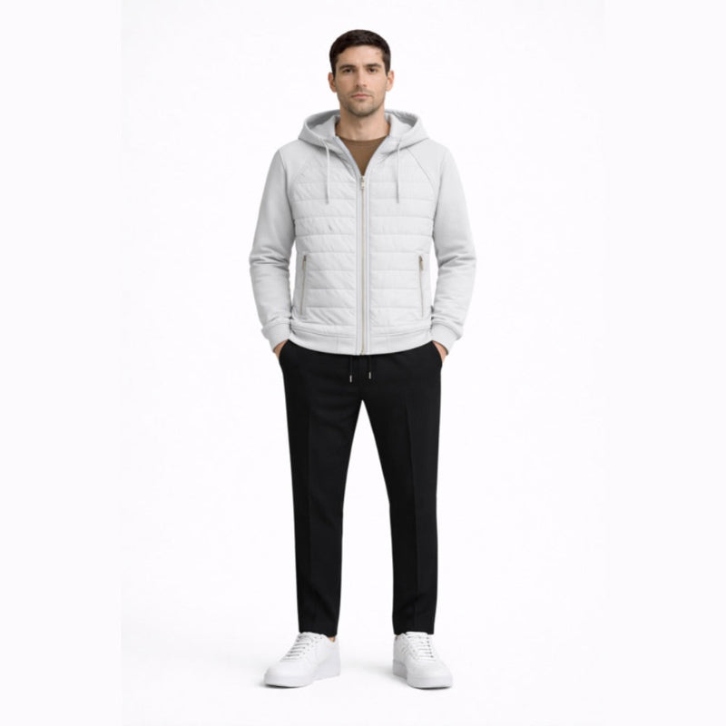 Man wearing a light gray quilted jacket, black pants, and white shoes on a white background