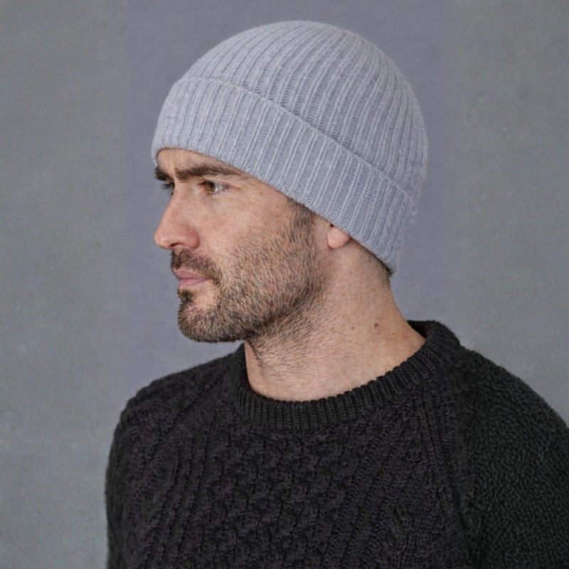 Man wearing a gray knit beanie and dark sweater against a gray background