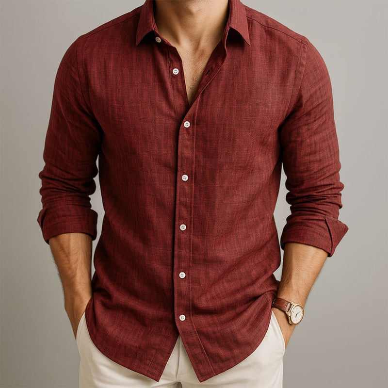 Man wearing a maroon button-up shirt with rolled-up sleeves on a neutral background