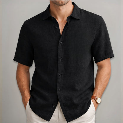 Man wearing a black short-sleeve shirt against a gray background