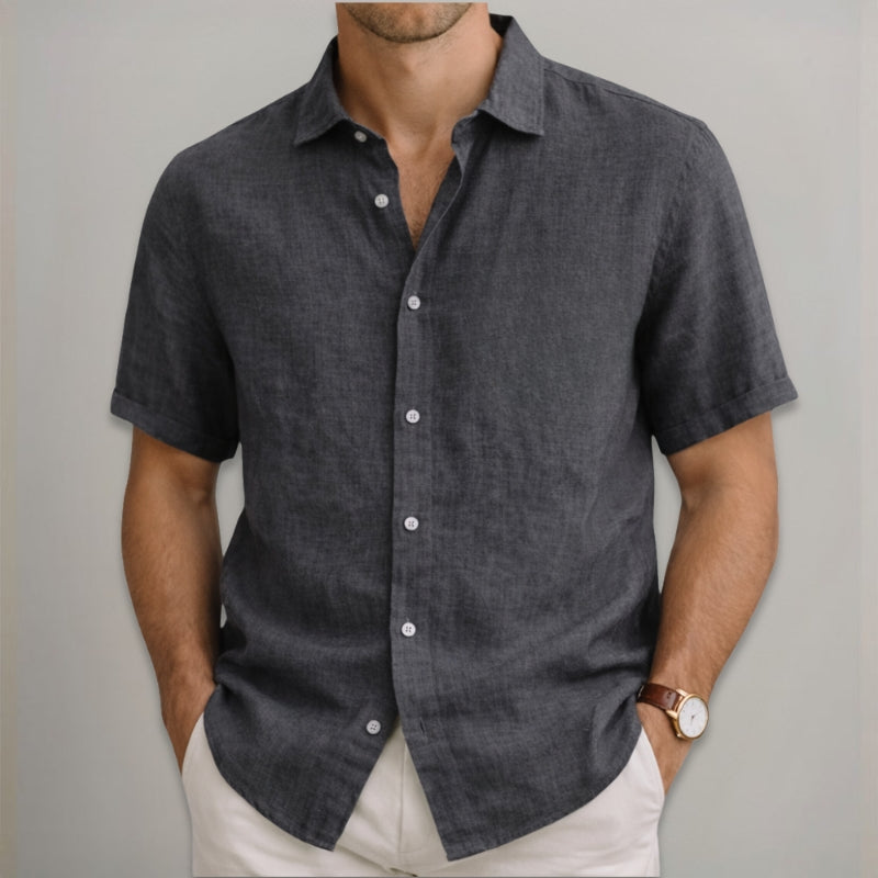 Man wearing a dark gray short-sleeve button-up shirt against a plain background