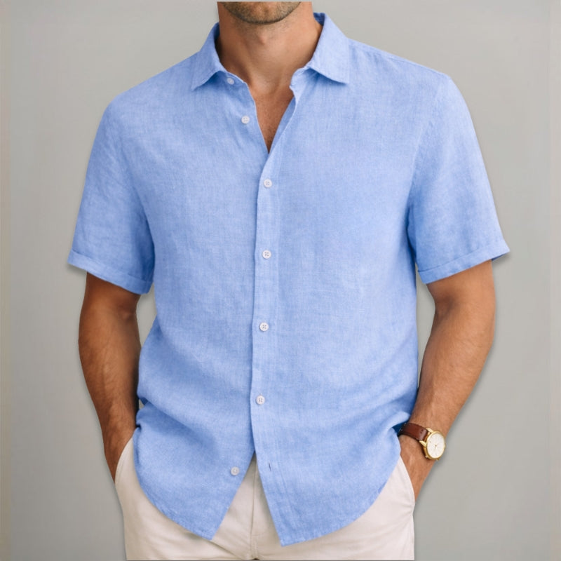 Man wearing a light blue short-sleeve shirt against a gray background