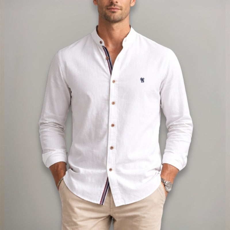 Man wearing a white button-up shirt with a small logo on a gray background