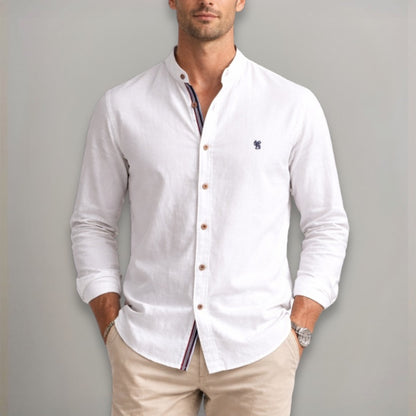 Man wearing a white button-up shirt with a small logo on a gray background