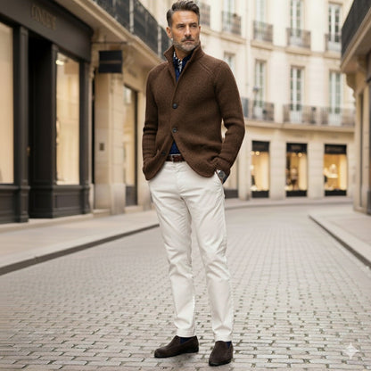 Mature model wearing brown Alfredo Gentleman Cardigan with white pants on a cobblestone street