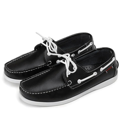 Pair of men’s leather boat shoes in black with white laces and white sole, premium casual moccasins with nautical stitching.