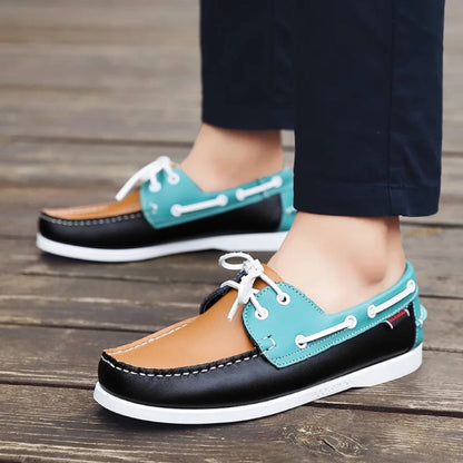 Multicolor men’s leather boat shoes with teal, tan, and black panels worn with trousers, stylish summer casual footwear.