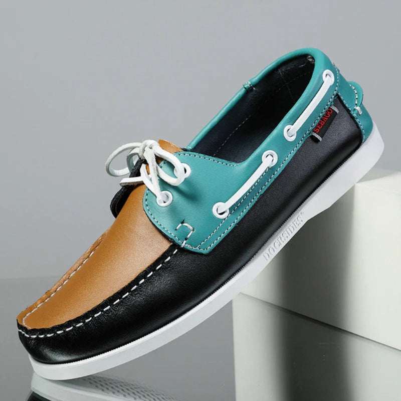 Men’s leather boat shoes in multicolor design – tan, teal, and black panels with white sole, modern nautical moccasins.